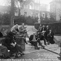 Velada literaria en el jardín del Marqués de la Vega-Inclán en el Real Alcázar, organizada por el Ateneo de Sevilla. El publicista Eugenio d'Ors leyendo unas páginas de un libro inédito ante un grupo de ateneístas: en el centro, el presidente del Ateneo Diego Angulo, Joaquín Bilbao, Juan Barrera y otros. 1921 ©ICAS-SAHP. Fototeca Municipal de Sevilla, fondo Sánchez del Pando