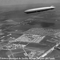 Vista aérea del barrio de Nervión trazado sobre el primitivo Cortijo del Maestre Escuela, propiedad del Marqués de Nervión. Gran Plaza, Ciudad Jardín y avenida Ramón y Cajal con el Matadero Municipal como límite meridional. En paralelo, vuelo del dirigible Graf Zeppelin. 16 de abril de 1930 ©ICAS-SAHP, Fototeca Municipal de Sevilla, archivo Sánchez del Pando