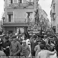 4. JUAN JOSÉ SERRANO GÓMEZ. Nuestro Padre Jesús de la Salud de la Hermandad de los Gitanos en la mañana del Viernes Santo. 1922-1923 La cofradía acaba de pasar por la estrecha calle Imagen junto a la iglesia de San Pedro y la calle Alcázares, actual Santa Ángela de la Cruz. A la izquierda, la calle Bolsa, desaparecida tras el ensanche urbanístico de finales de 1940. © ICAS-SAHP, Fototeca Municipal de Sevilla, Archivo Serrano