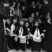 30. RAFAEL CUBILES LÓPEZ. Escuela de cofrades. 1975. Los niños monaguillos, desfilan en el cortejo de la Hermandad de Santa Cruz delante de sus titulares, el Cristo de las Misericordias y la Virgen de los Dolores. La participación en estas experiencias de religiosidad tradicional se inicia desde muy temprana edad. © ICAS-SAHP, Fototeca Municipal de Sevilla, Archivo Cubiles