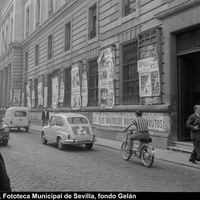 Fachada del Palacio de Justicia con cartelería de cines, teatros y salas de fiesta. En primer término, la Oficina de la Junta Municipal del Censo Electoral. Tráfico rodado en doble sentido sobre la calle adoquinada. 17 de junio de 1969. ©ICAS-SAHP, Fototeca Municipal de Sevilla, fondo Gelán