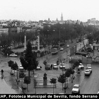 Vista cenital del lado norte de la Alameda. En primer término la escultura de La Niña de los Peines. A la derecha, el cuartel de la Policía Armada ya derribado. El solar sería utilizado como almacén, sede efímera de instalaciones deportivas y después un cine de verano  hasta la construcción en 2006 de la actual Comisaría de Policía. 1975 ©ICAS-SAHP, Fototeca Municipal de Sevilla, fondo Serrano