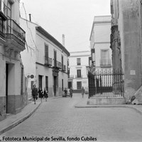 11. Calle Mateos Gago. A la derecha, la iglesia de Santa Cruz, con la antigua verja que se desmontó para la alineación de la calle. A la izquierda, la embocadura de la calle Guzmán el Bueno y la Casa Salinas. Al fondo, la Casa Fabiola. 1965 ©ICAS-SAHP, Fototeca Municipal de Sevilla, fondo Cubiles