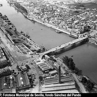 Vista aérea del río Guadalquivir a su paso por Sevilla. Los puentes dan acceso a los barrios de la margen derecha: el de Triana, que desemboca en la plaza del Altozano, y el nuevo puente de San Telmo (en construcción) que llegará a la plaza de Cuba. 1929-1930 ©ICAS-SAHP, Fototeca Municipal de Sevilla, fondo Sánchez del Pando