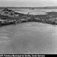 Vista de la Plaza de Cuba y su entorno durante la crecida del río Guadalquivir. En la plaza un cartel de la Inmobiliaria Los Remedios, S. A. Las aguas cubren el terreno del futuro barrio de este nombre. A la izquierda, el convento de Los Remedios. 1936. ©ICAS-SAHP, Fototeca Municipal de Sevilla, fondo Serrano