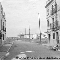 Calle Virgen de Loreto y farmacia Los Remedios. Explanada donde se construirá la parroquia de Los Remedios. Al fondo, viviendas de la Obra Nacional (calles Virgen de la Victoria, Miño y Padre Damián). Ca. 1955 ©ICAS-SAHP, Fototeca Municipal de Sevilla, archivo Serrano