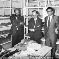 28.- Visita del alcalde Manuel del Valle al Servicio de Archivo, Hemeroteca y Publicaciones. Alfonso Braojos le muestra las dependencias donde se procede a la ordenación y catalogación del Archivo Serrano, germen de la actual Fototeca Municipal de Sevilla. Le acompaña el delegado de Cultura Bernardo Bueno. 21 de marzo de 1990 ©ICAS-SAHP, Fototeca Municipal de Sevilla, fondo Alcaldía de Sevilla